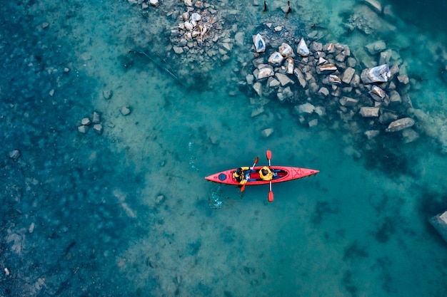 Kostenloses Foto mann mit zwei athleten schwimmt auf ein rotes boot im fluss