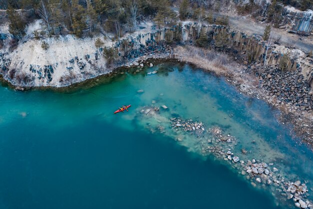 Mann mit zwei Athleten schwimmt auf ein rotes Boot im Fluss