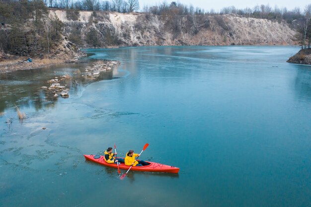 Mann mit zwei Athleten schwimmt auf ein rotes Boot im Fluss