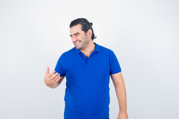 Mann mittleren Alters, der im blauen T-Shirt wegschaut und fröhlich aussieht