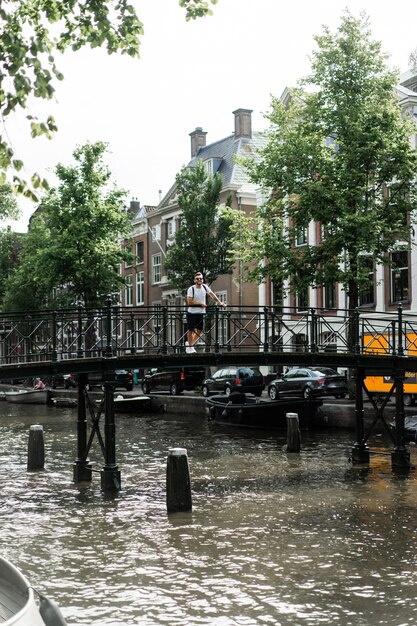 Mann posiert auf der Brücke in Amsterdam.