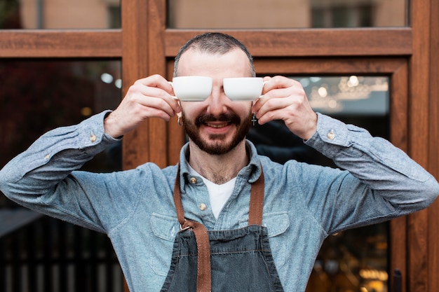 Mann posiert mit Kaffeetassen