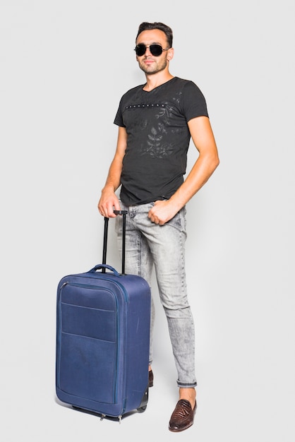 Mann posiert mit Koffer