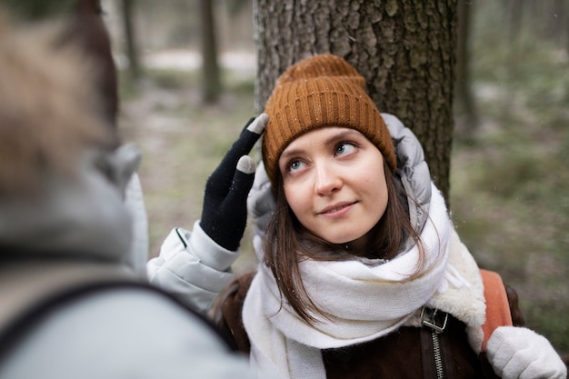 Mann repariert die Mütze einer Frau, während er im Wald für einen Roadtrip ist