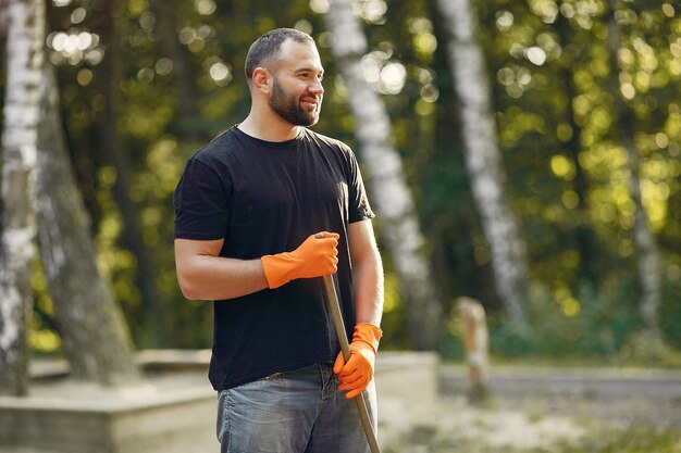 Mann sammelt Blätter und säubert den Park