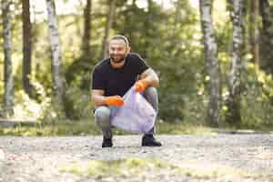 Kostenloses Foto mann sammelt müll in müllsäcken im park