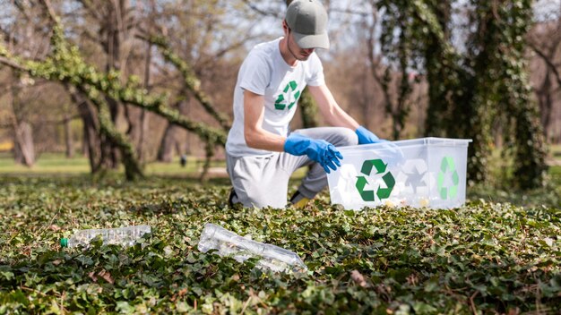 Mann sammelt Plastikmüll in einem verschmutzten Park