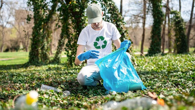 Mann sammelt Plastikmüll in einem verschmutzten Park