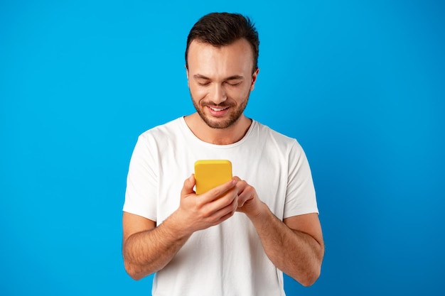 Mann schaut auf das Telefon, das isoliert auf blauem Hintergrund steht