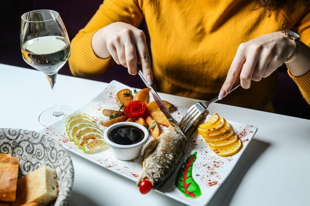 Mann schneiden gegrillten Fisch mit hausgemachter Kartoffel-Zitronenbrot-Sauce