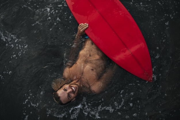 Mann schwimmt mit seinem roten Surfbrett