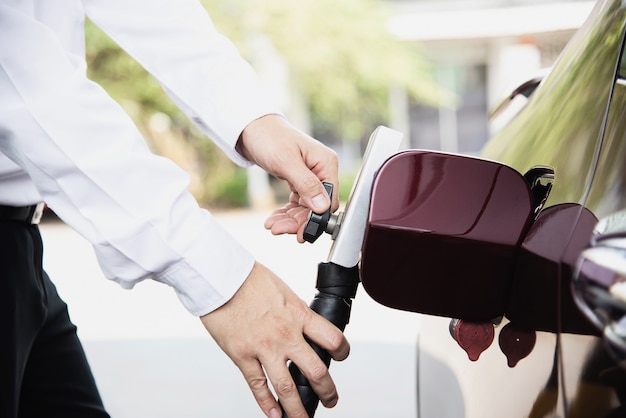 Mann setzt NGV, Erdgasfahrzeug, Hauptzufuhr zu einem Auto an der Tankstelle in Thailand