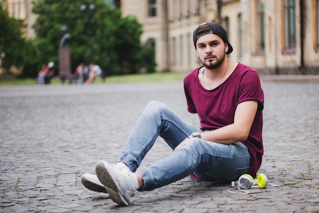 Kostenloses Foto mann sitzt auf block stein posiert