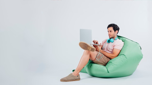 Mann sitzt auf Couch mit Laptop