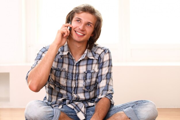 Mann sitzt auf dem Boden und spricht per Telefon