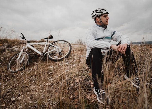 Mann sitzt auf dem Gras neben seinem Mountainbike