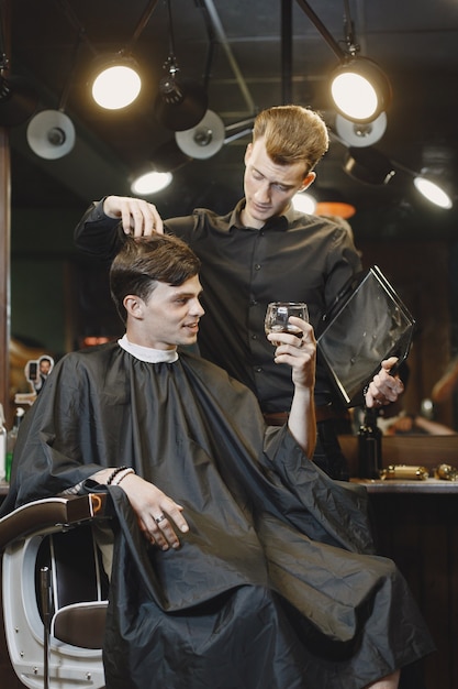 Mann sitzt auf einem Stuhl. Friseur mit einem Kunden. Guy trinkt einen Whisky.