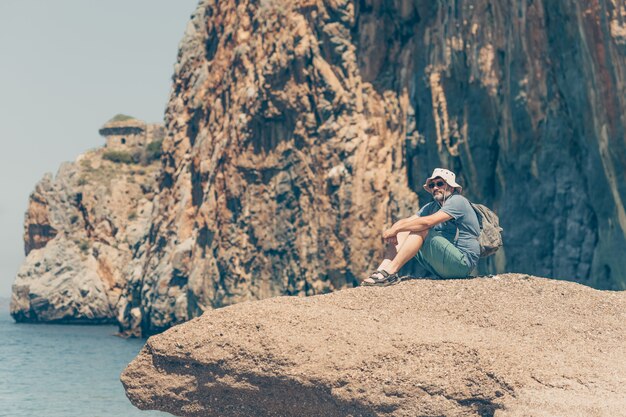 Mann sitzt auf Felsen und betrachtet seinen Strand während des Tages