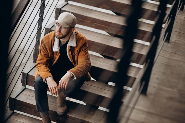 Mann sitzt auf Treppe in Winterjacke