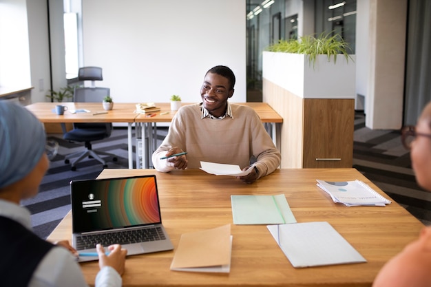 Kostenloses Foto mann sitzt für ein vorstellungsgespräch im büro am schreibtisch mit seinem arbeitgeber his