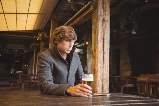 Mann sitzt in der Bar mit Glas Bier auf Tisch