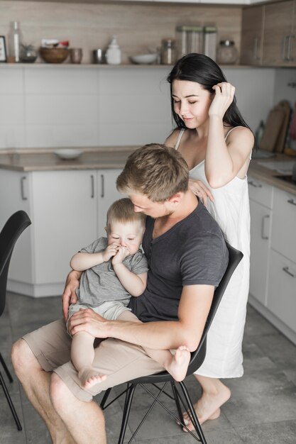 Mann sitzt mit seinem Sohn und seiner Frau hinter dem Stuhl