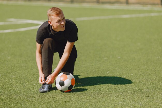 Mann spielen Socerl im Park. Turnier auf Mini-Footbal. Kerl in einem schwarzen Sportanzug.