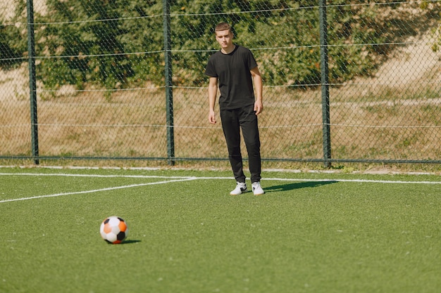 Mann spielen Socerl im Park. Turnier auf Mini-Footbal. Kerl in einem schwarzen Sportanzug.