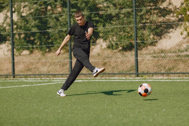 Mann spielen Socerl im Park. Turnier auf Mini-Footbal. Kerl in einem schwarzen Sportanzug.