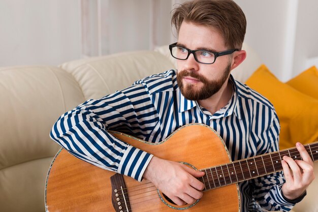 Mann spielt Gitarre zu Hause