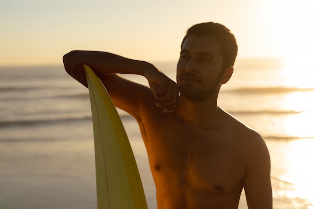 Mann stehend mit surfbrett am strand