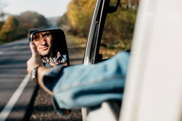 Mann stellt seinen Spiegel im Auto ein