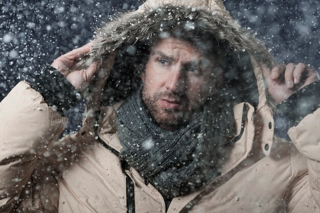 Mann trägt eine Winterjacke, während es schneit