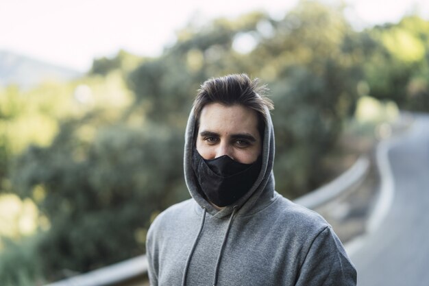 Mann trägt einen Pullover und eine Gesichtsmaske auf einer Straße