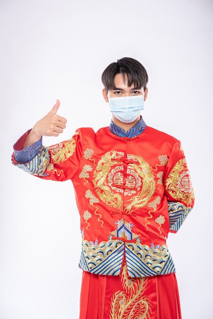 Kostenloses Foto mann tragen cheongsam anzug und maske zeigen den besten weg zum einkaufen zum schutz von krankheiten