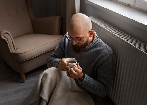 Kostenloses Foto mann trinkt heißes getränk während der energiekrise