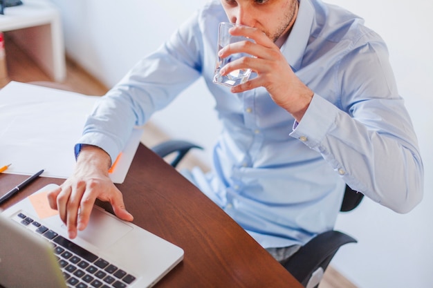 Kostenloses Foto mann trinkwasser sitzt am tisch