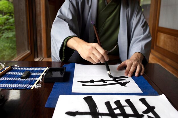 Mann übt japanische Handschrift mit einer Auswahl an Werkzeugen