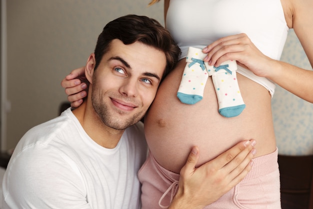 Mann umarmen Bauch seiner schwangeren Frau versuchen, Baby zu hören