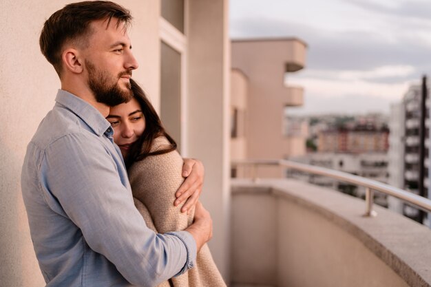 Mann und Frau auf Balkon bei Sonnenuntergang in der Stadt