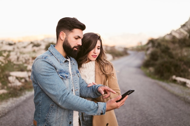 Mann und frau, die am telefon auf straße schauen