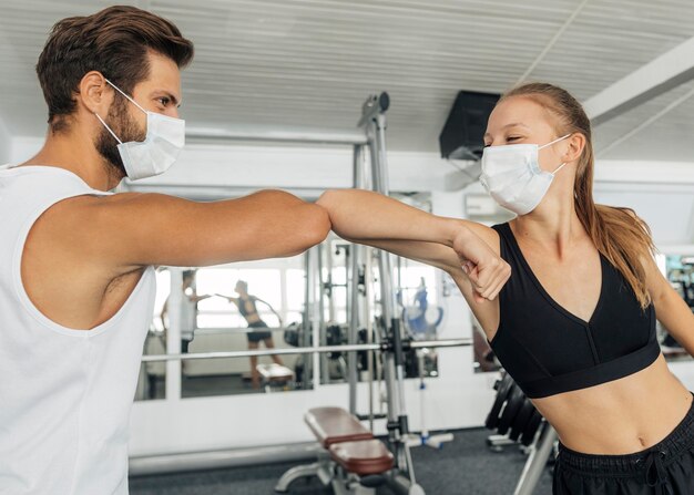 Mann und Frau, die den Ellbogengruß im Fitnessstudio tun