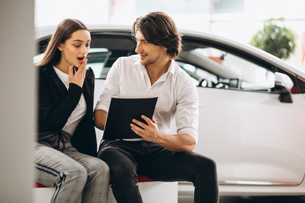 Mann und Frau, die ein Auto in einem Autosalon wählen