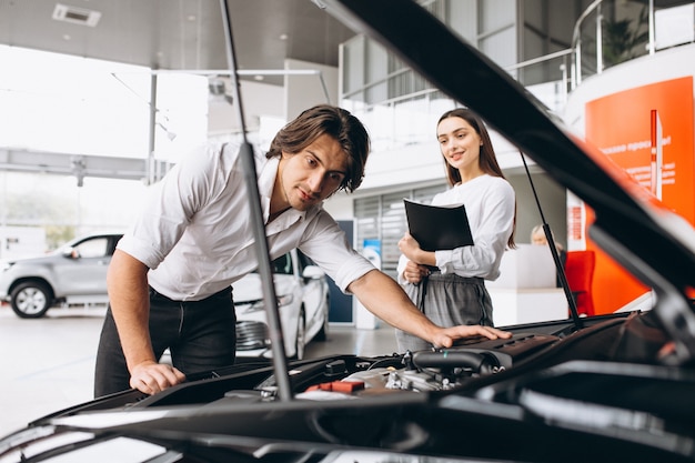 Mann und Frau, die ein Auto in einem Autosalon wählen