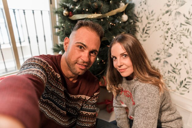 Mann und Frau, die selfie nahe Weihnachtsbaum nehmen