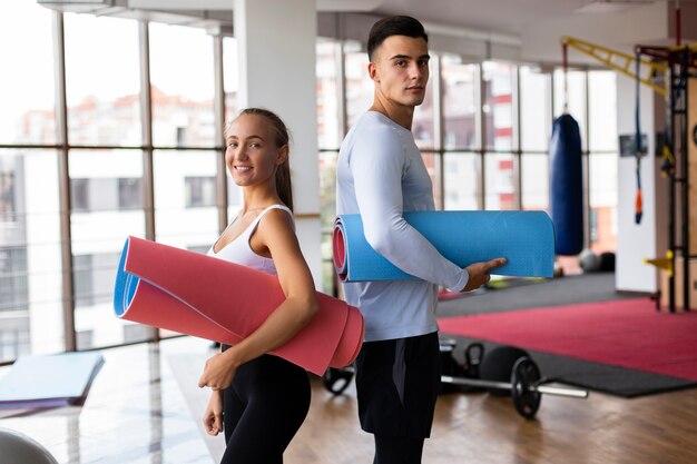 Mann und Frau, die Yogamatten halten