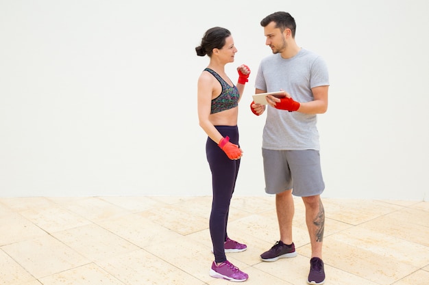 Mann und Frau diskutieren Trainingsplan mit eingewickelten Händen