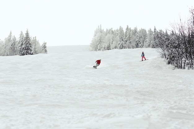 Mann und Frau gehen den Hügel auf den Snowboards hinunter