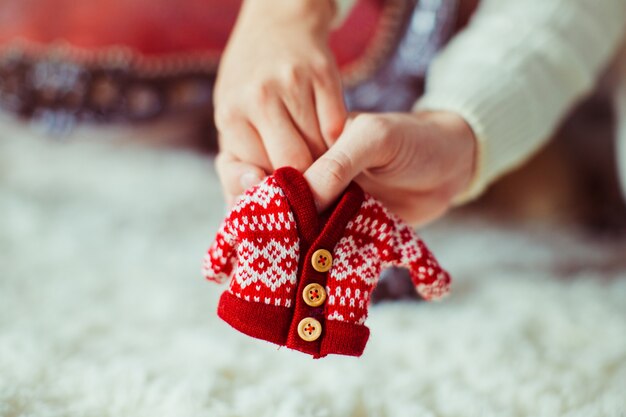 Mann und Frau halten in ihren Händen Pullover für Neugeborenes Baby