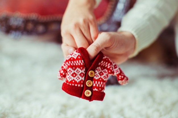 Mann und Frau halten in ihren Händen Pullover für Neugeborenes Baby